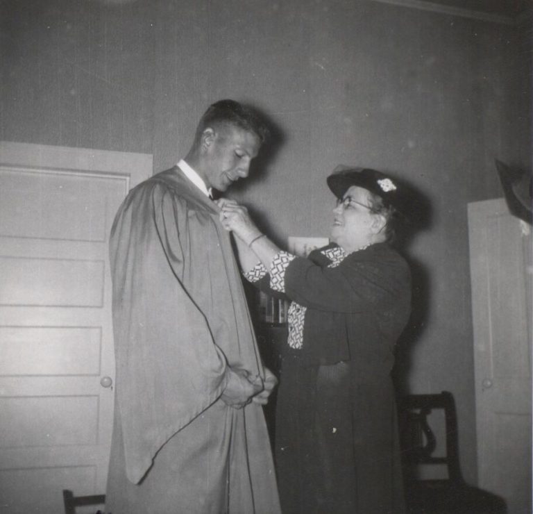 Joe Michalka in a graduation gown while Mom fastens a pin, in a family snapshot