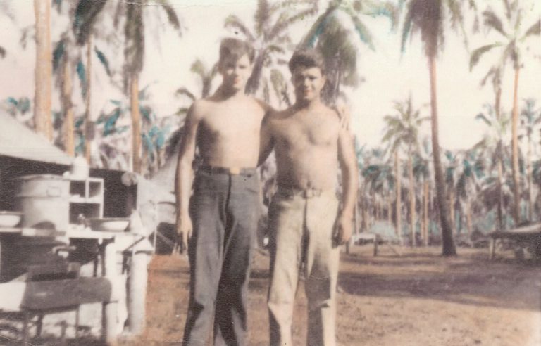 Two young men standing among palm trees in the Pacific, a hand-tinted photo from the John Cardinal family photos