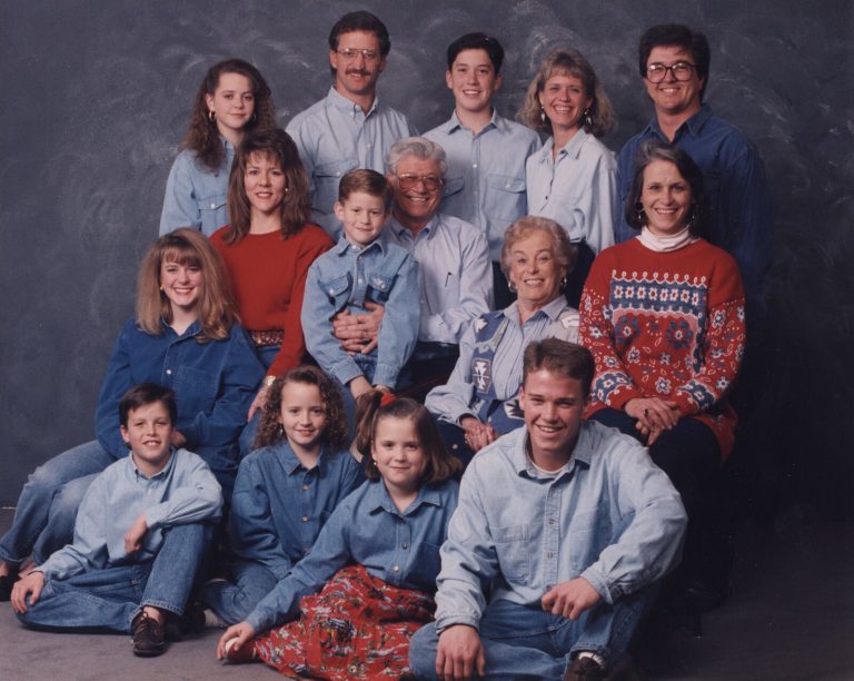 Large family group in denim and red tops posed in a studio, from the John Cardinal family photos