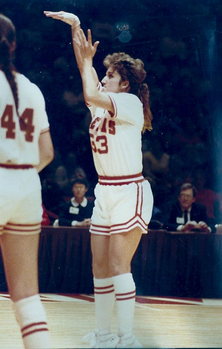 Kamie Ethridge following through on a shot in a white Texas uniform with a teammate in the foreground