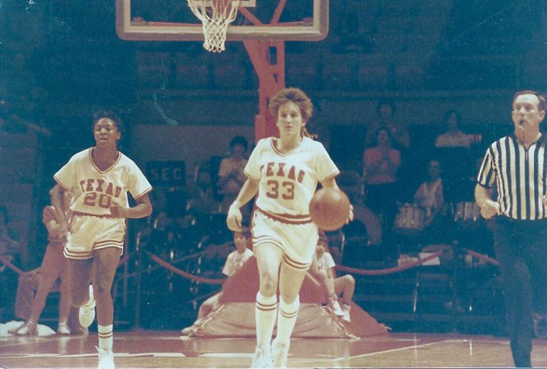 Kamie Ethridge dribbling upcourt in a Texas uniform as a teammate and a referee follow