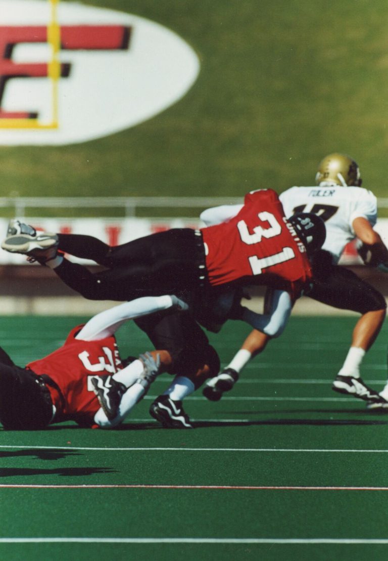 Kevin Curtis, number 31 in a red Texas Tech jersey, diving to tackle a ball carrier