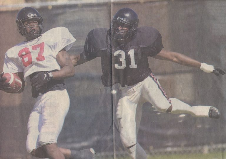 Kevin Curtis, number 31 in a dark jersey, stretching to defend a ball carrier in a white number 87 jersey