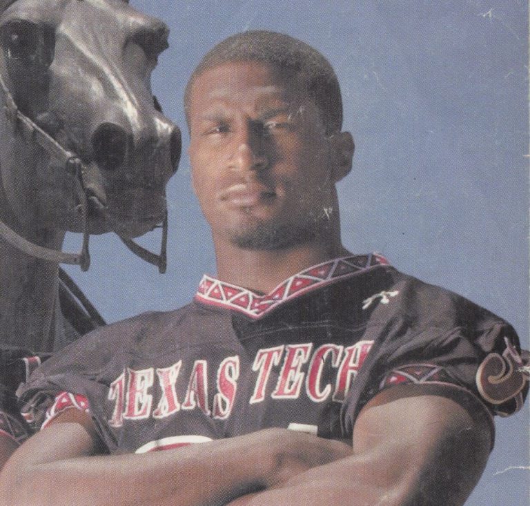 Kevin Curtis in a Texas Tech jersey with arms crossed beside a horse statue