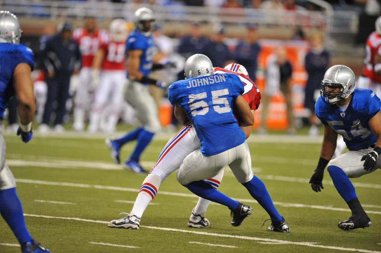 Landon Johnson, in a blue No. 55 JOHNSON jersey, wrapping up a ball carrier in a red uniform during a game