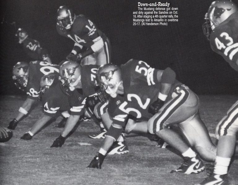 Landon Johnson's Coronado Mustangs defense set in stances at night against the Sandies, from a yearbook