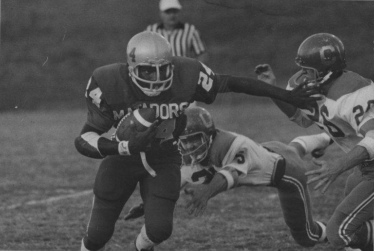 Larry Isaac in a Matadors number 24 jersey carrying the ball and stiff-arming a defender
