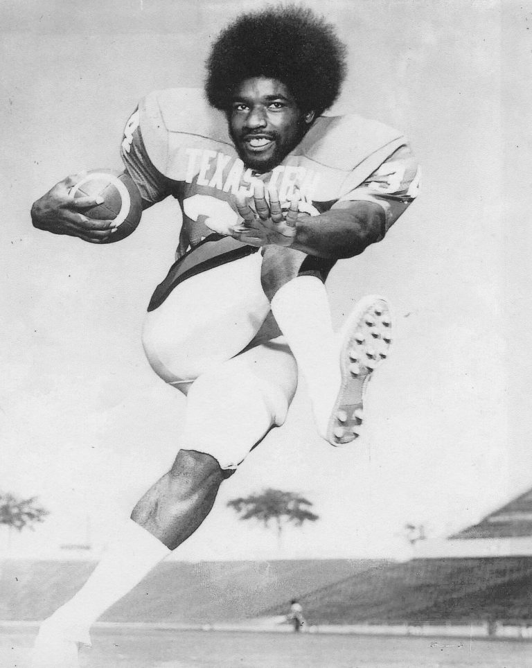 Larry Isaac in a Texas Tech jersey leaping with a high knee while carrying the ball in an empty stadium