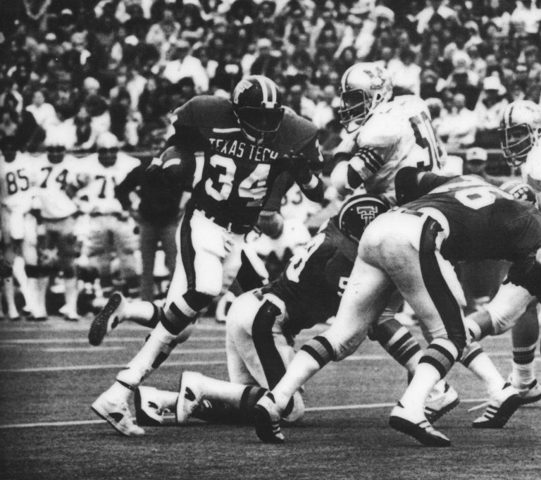 Larry Isaac carrying the ball for Texas Tech, number 34, with a stadium crowd behind