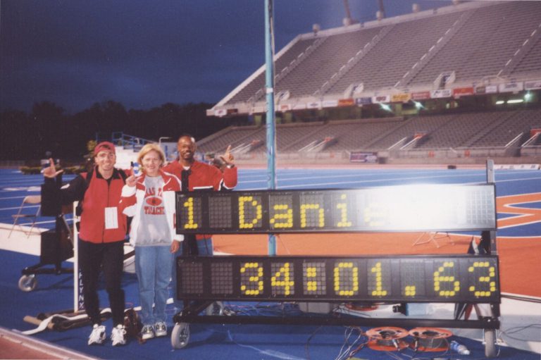 Leigh Daniel Cordes' first-place time of 34:01.63 on a stadium scoreboard beside three people in Texas Tech gear