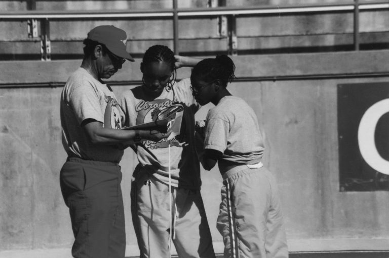 Melvin Houston in a cap coaching two runners, black-and-white program photo