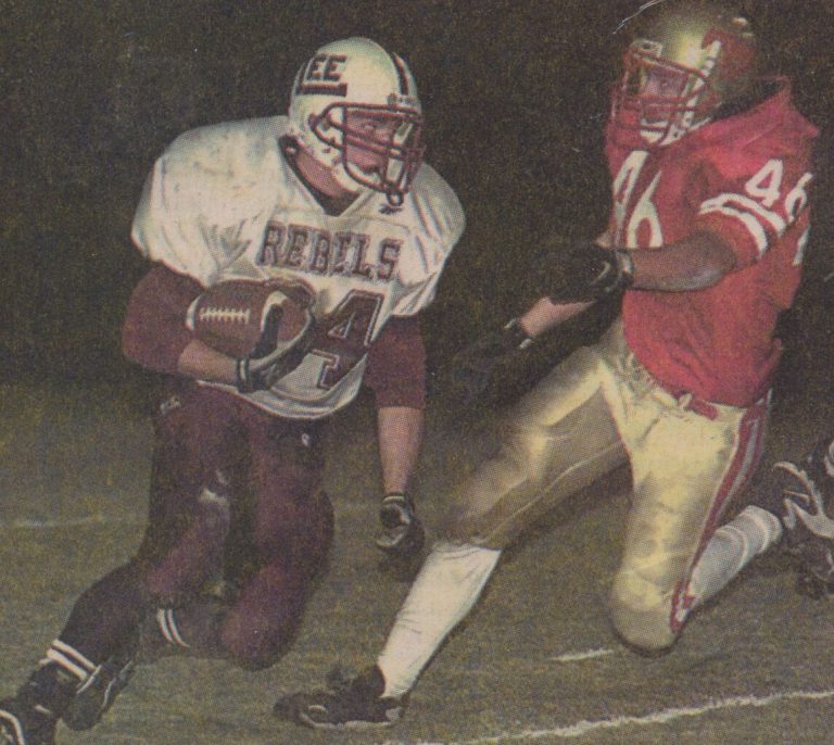 Mike Smith, number 46 in a red Coronado jersey, chasing a Lee Rebels ball carrier in a night game
