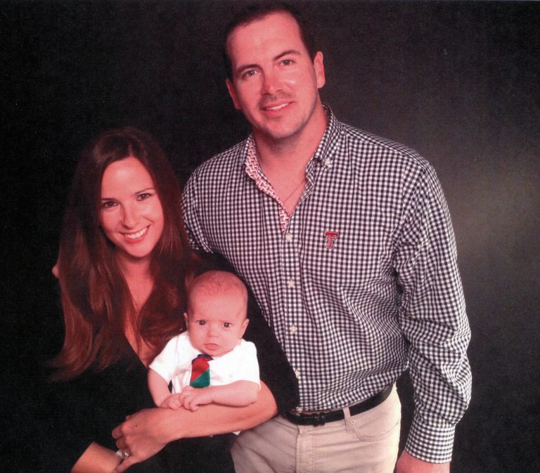 Mike Smith in a checked shirt with a smiling woman and a baby in a family portrait