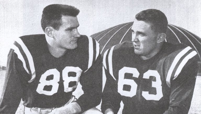 Pat Hartsfield in a number 88 jersey with a teammate in number 63, posed in front of a running track