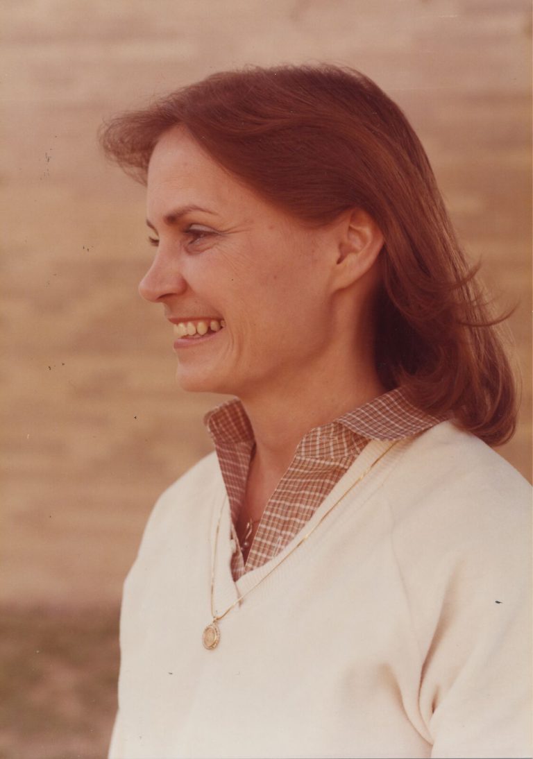 Patty Jones smiling in profile in a cream sweater over a checked collar with a gold pendant, 1970s portrait