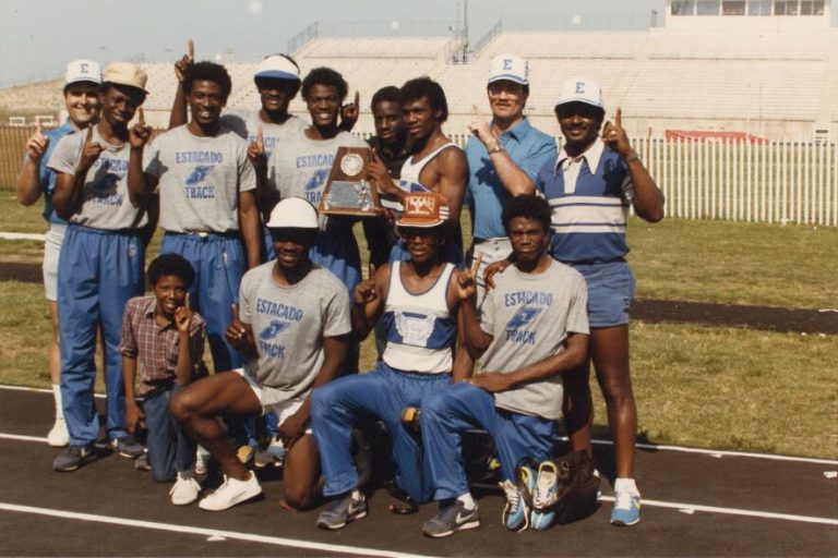 Estacado Track team members pointing up with a trophy on the track, from Percy Hines' collection