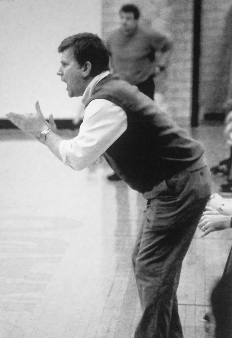 Randy Dean coaching on the sideline with hands outstretched, black and white