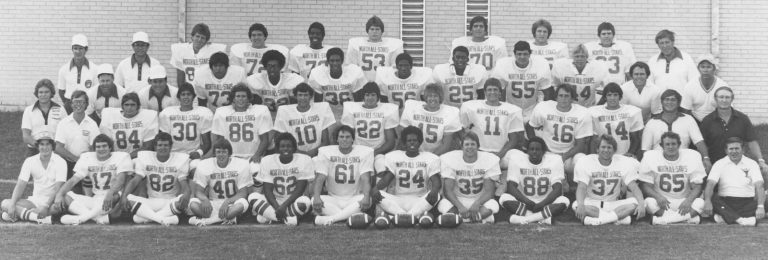 North All-Stars football team and coaches posed in rows against a brick wall, from the Ron Reeves collection