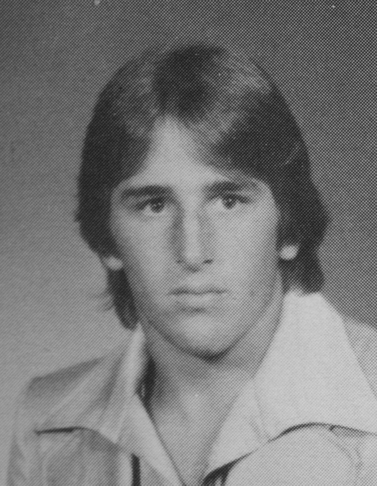 Ron Reeves in a black-and-white yearbook-style portrait wearing an open-collared shirt