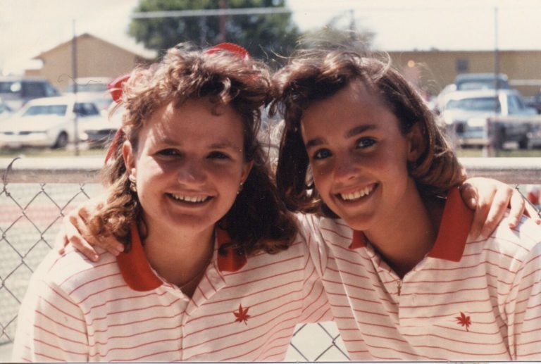 Tanya Hamilton Bryant and Lara Mahaney smiling with arms around each other in matching striped polos