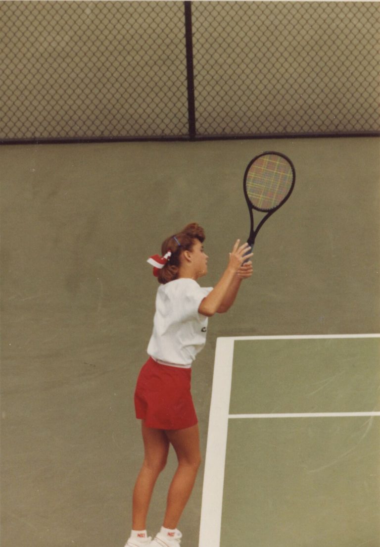 Tanya Hamilton Bryant and Lara Mahaney: a player in a visor and red shorts reaching up to serve on a green court