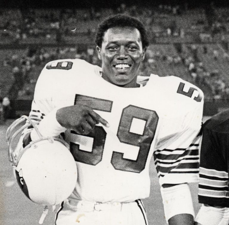 Thomas Howard smiling in a No. 59 Cardinals jersey while carrying a helmet, in a black-and-white photo