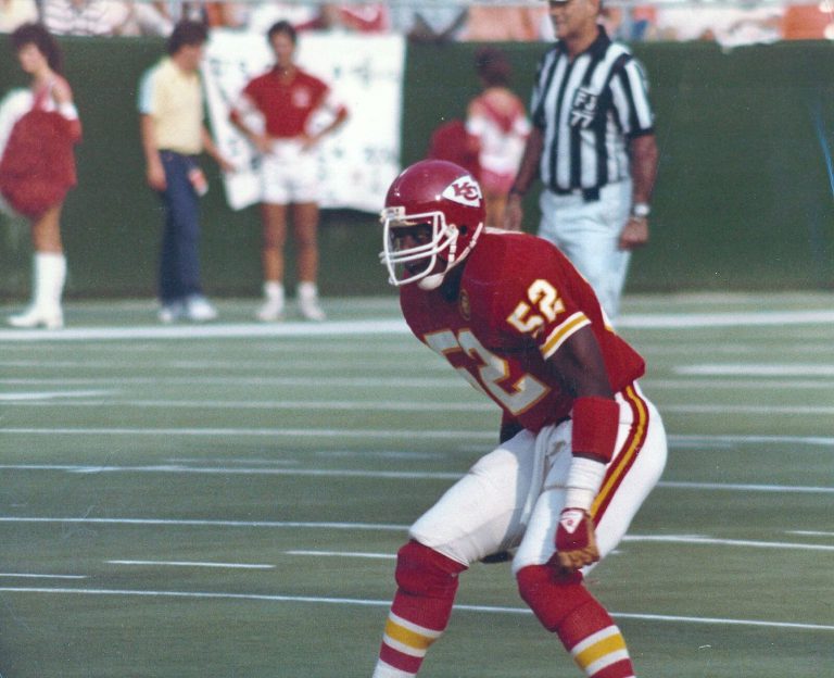 Thomas Howard in a red Kansas City Chiefs No. 52 uniform in a ready stance on the field