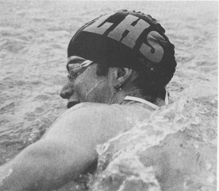 Thomas Klement in an LHS swim cap and goggles swimming breaststroke, black-and-white yearbook photo