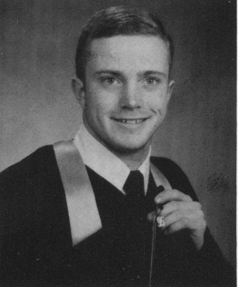 Thomas Klement smiling in a graduation gown, black-and-white yearbook senior portrait