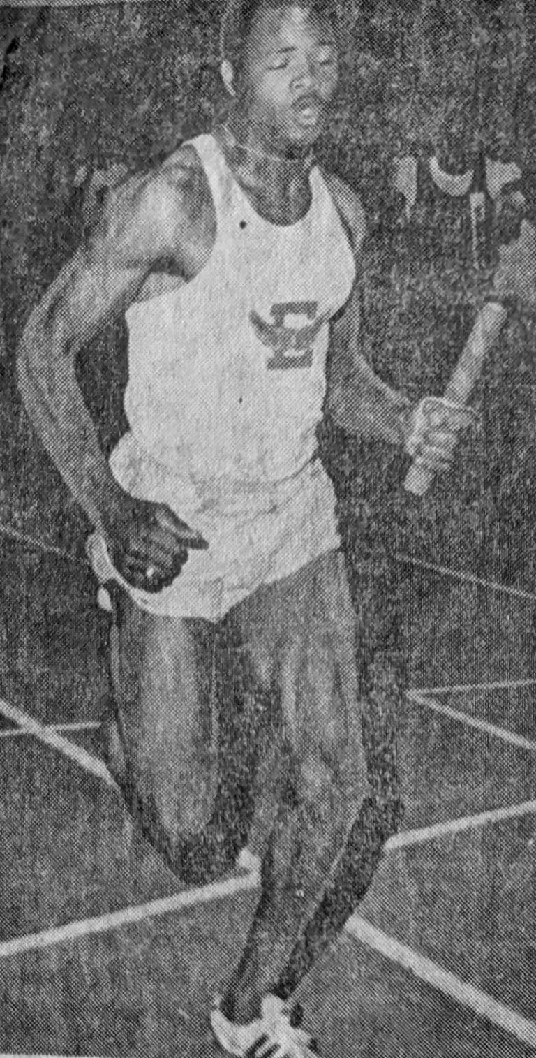 1970 State Champion Track Team anchorman William Hall running with the baton in the 440-yard relay, from a newspaper