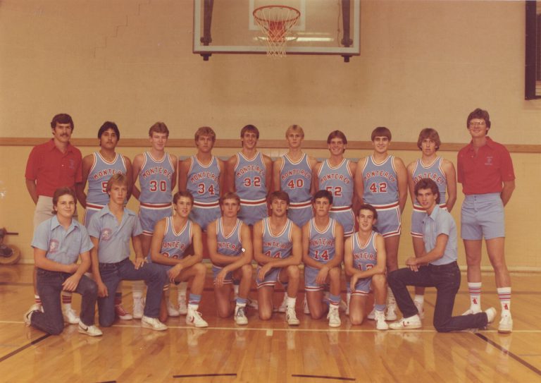 Monterey basketball team posing in a gym in light blue uniforms with two men in red shirts, from the Grady Newton collection