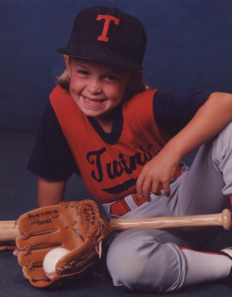 Child in a Twins baseball uniform with a glove, bat and ball, studio portrait from the Amanda Parsons collection