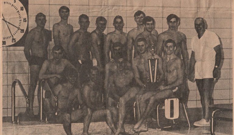 Ron Holihan's Eastern Kentucky Eels swim team posing at the pool with a trophy, from a newspaper clipping