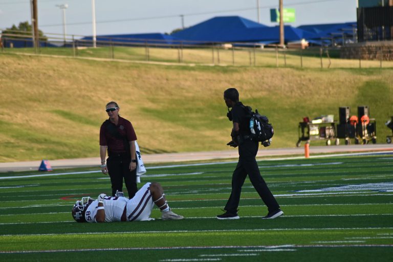 Lubbock High athletic trainer walking toward a downed player on the field, from the Anthony Peppers collection