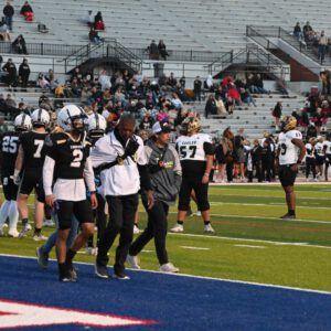 Anthony Peppers walks the sideline with Lubbock High football players during a game.