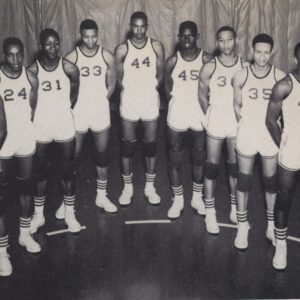 Dunbar Panthers basketball players in numbered jerseys stand shoulder to shoulder on the court in the early 1960s.