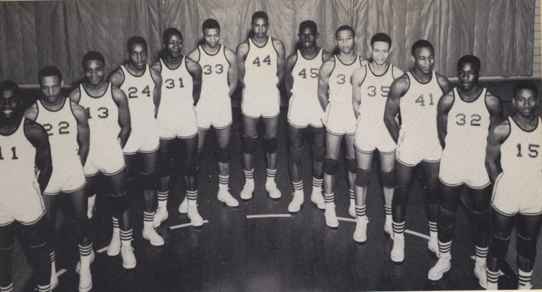 Dunbar Panthers basketball players in numbered jerseys stand shoulder to shoulder on the court in the early 1960s.