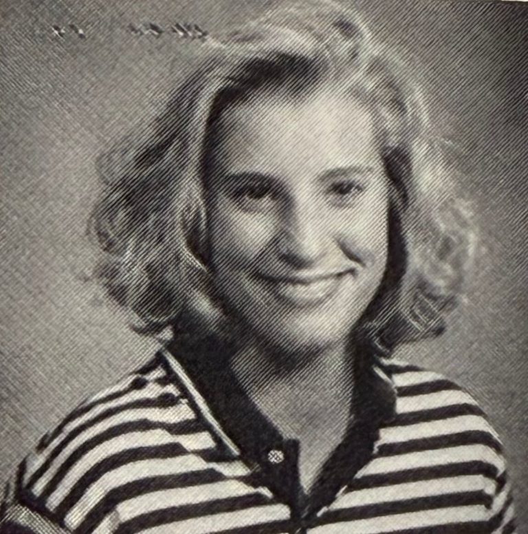 Kim Sumrall smiling in a striped polo shirt, yearbook portrait