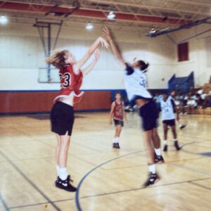 Kim Sumrall, wearing number 23, leaps to contest an opponent's shot during a gym game