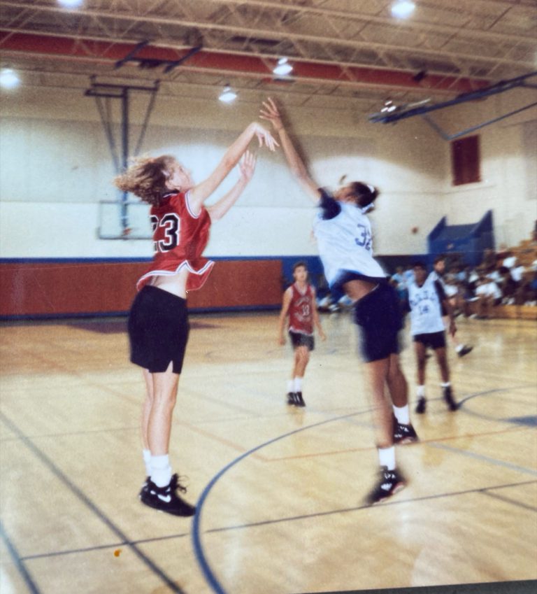 Kim Sumrall, wearing number 23, leaps to contest an opponent's shot during a gym game