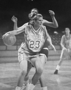 Kim Sumrall in her Monterey number 23 uniform driving with the basketball during a 1990s game