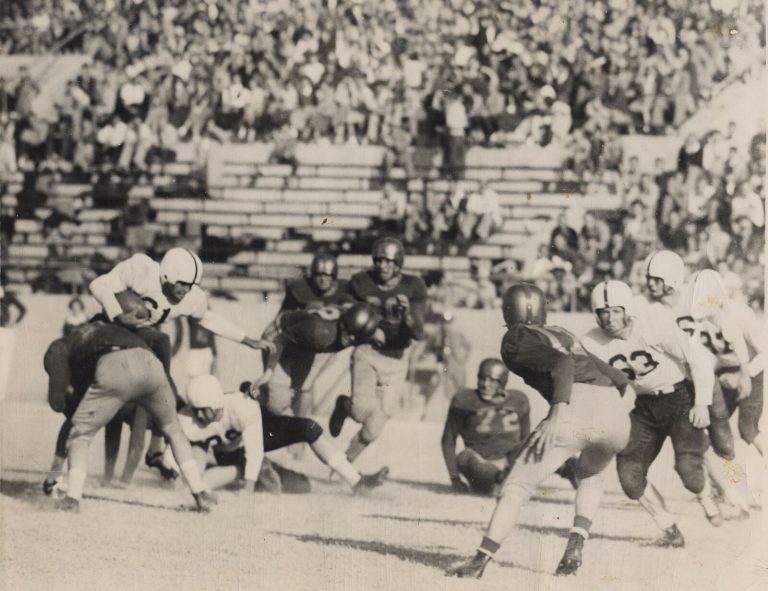 Football game action before a packed grandstand, a print from the Mac Taylor collection