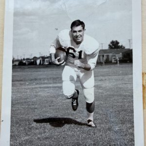 Mac Taylor, number 61, runs toward the camera with the football in a posed Lubbock High photo
