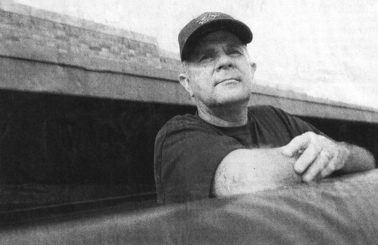 Robert "Prof" Ramos in a ball cap looks out from the Estacado dugout in a newspaper photo marking his retirement.