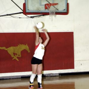 Robyn Smith sets a volleyball in the Coronado gym wearing her No. 34 Lady Mustangs jersey.
