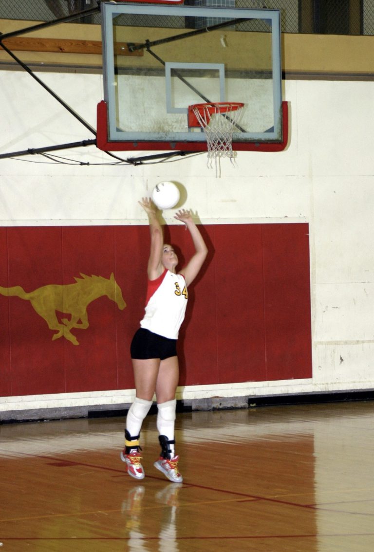 Robyn Smith sets a volleyball in the Coronado gym wearing her No. 34 Lady Mustangs jersey.