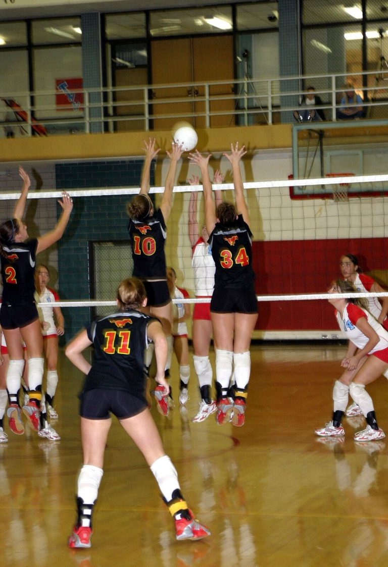 Robyn Smith Everson, number 34 in black, jumping with a teammate to block at the net