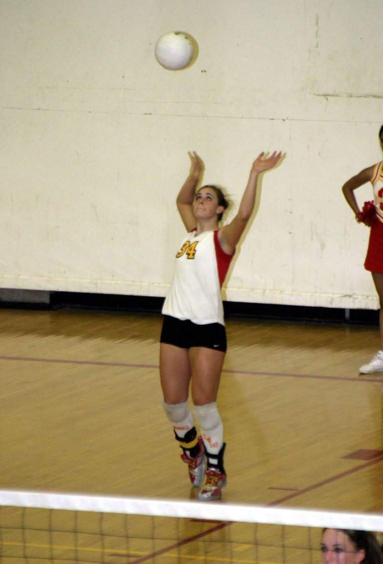 Robyn Smith Everson in a white number 34 jersey with hands up to set a high ball