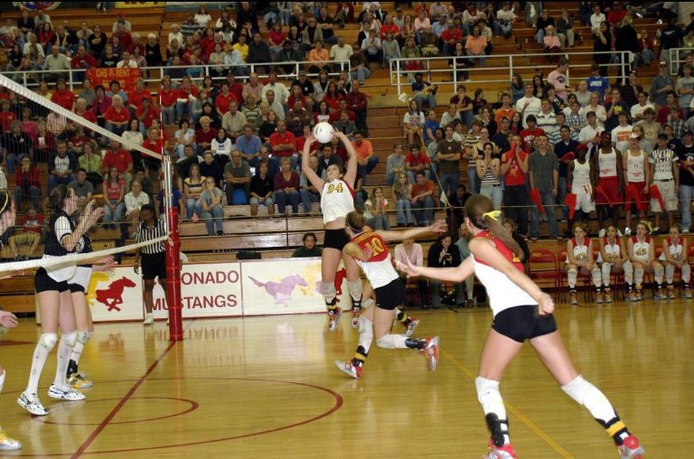 Robyn Smith Everson setting the ball at the net with the Coronado Mustangs banner behind