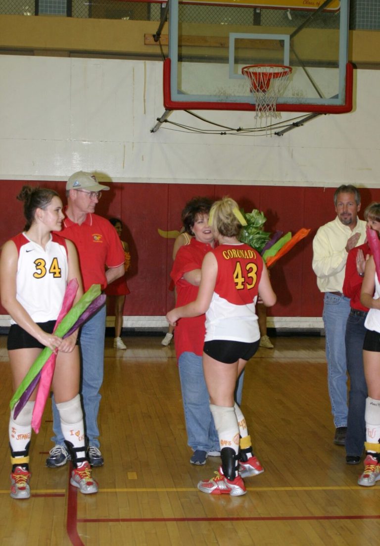 Robyn Smith Everson, number 34, holding colorful flowers on the volleyball court during a ceremony